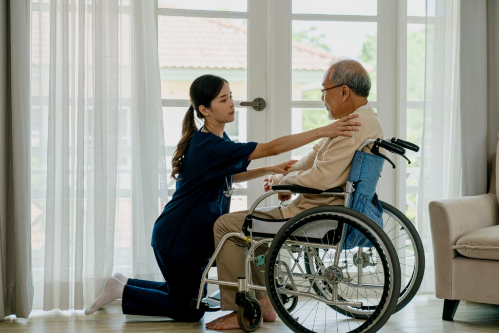 Compassionate caregiver comforting elderly man in wheelchair at home.