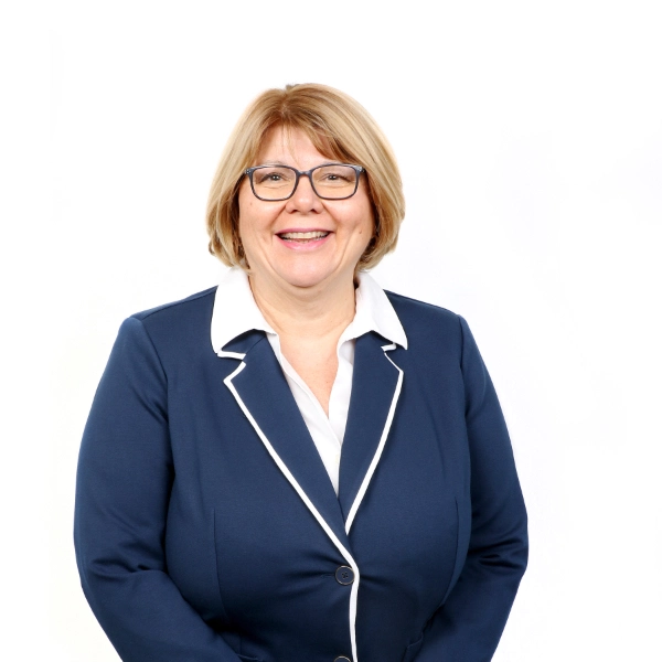 Kindhearted senior care professional smiling in professional attire, promoting compassionate elderly support services.
