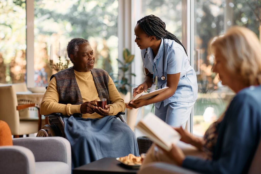 Elderly man in wheelchair receiving compassionate care from nurse in cozy home setting.